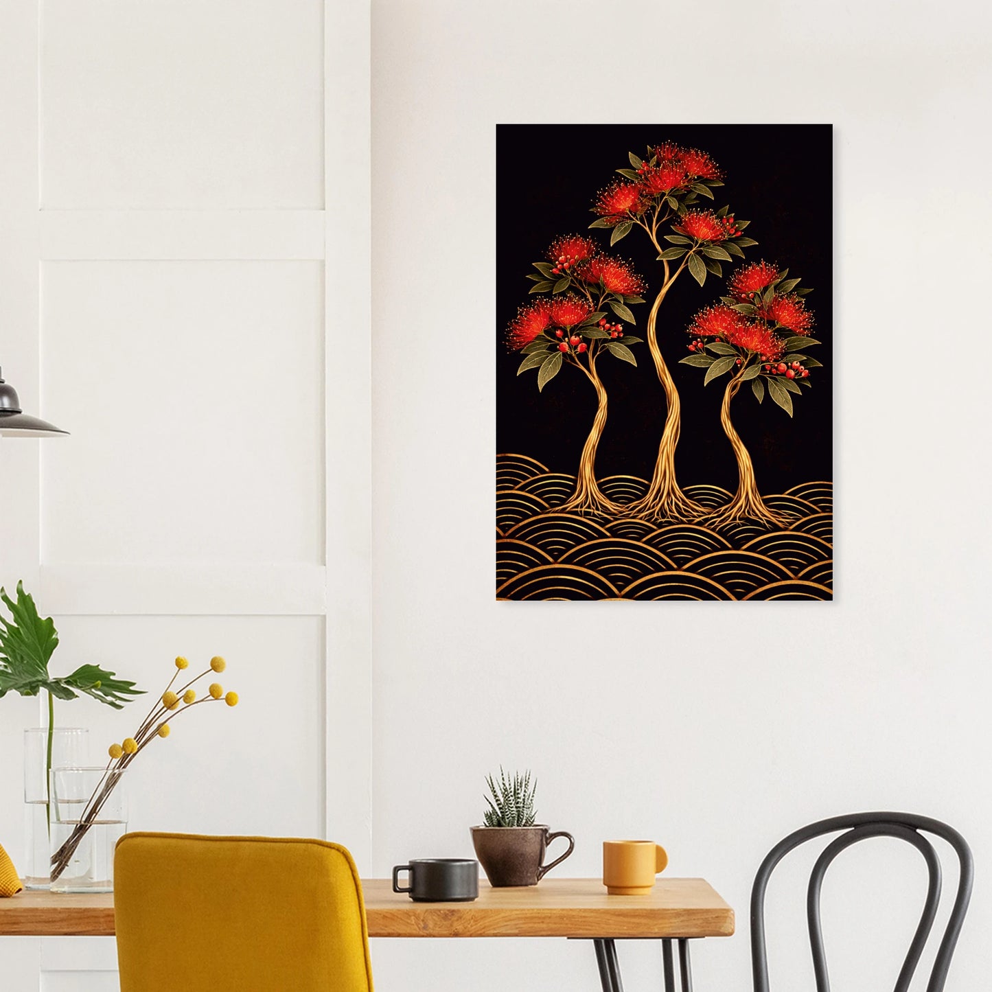A vertical wall art print depicting three stylized red-flowering trees with gold roots over a black background and gold wave patterns, displayed on a white wall above a dining table with chairs and mugs.