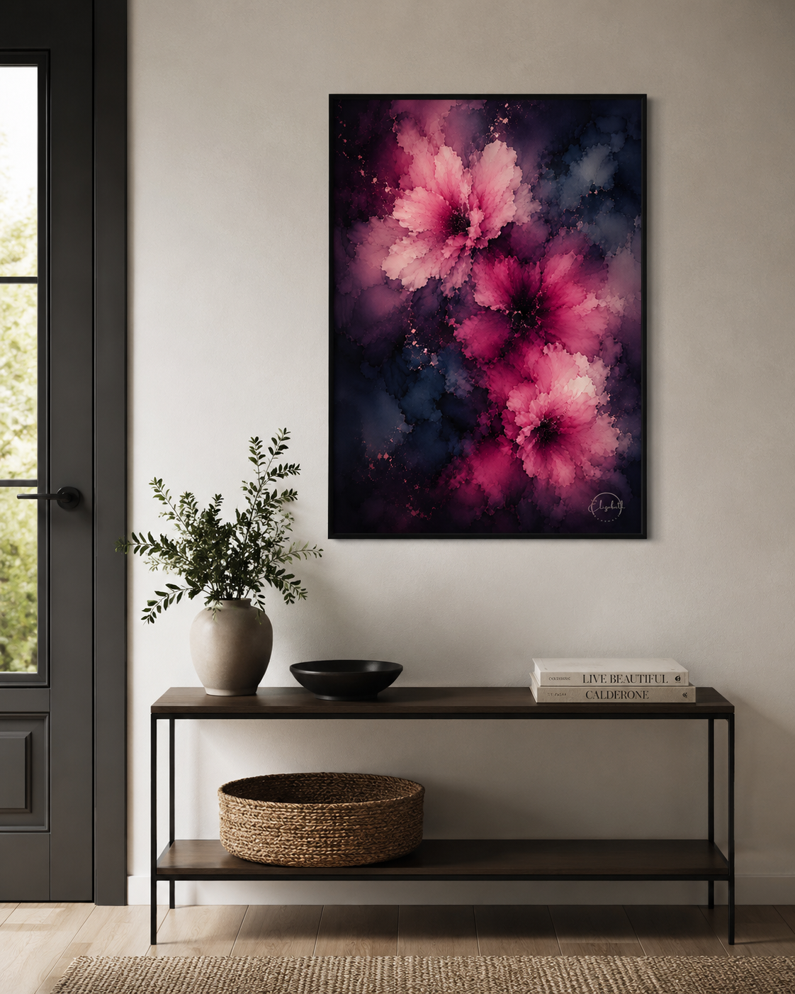 A vertical framed canvas print featuring vibrant pink and magenta watercolor-style flowers against a dark navy and black background, displayed on a light gray wall above a dark wood console table with decorative items.