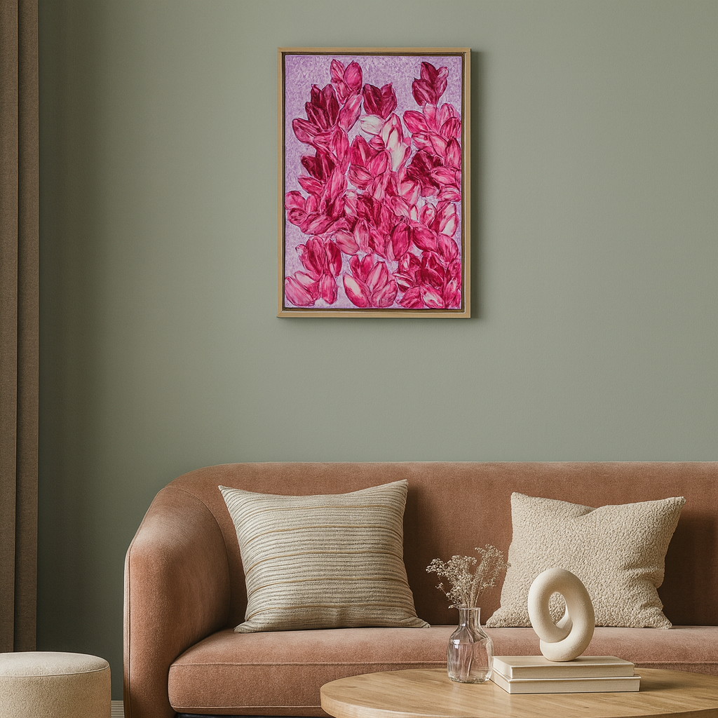 A framed floral wall art print with bright pink flowers on a lavender background, hanging above a mauve sofa in a styled living room.