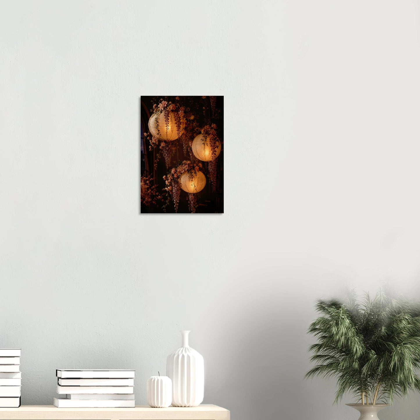 Three glowing paper lanterns hanging in a dim interior, decorated with cascading pink wisteria flowers and green leaves.