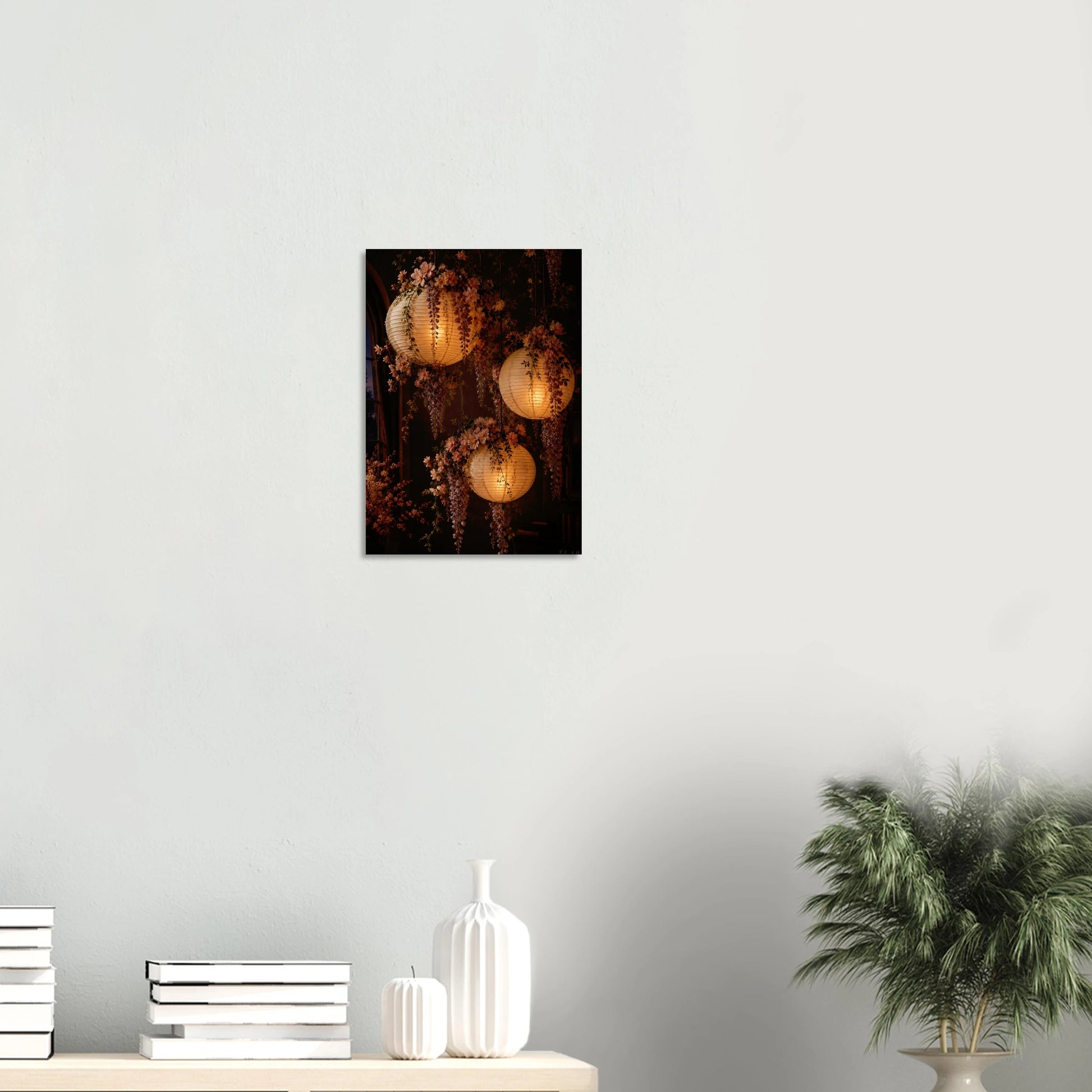 Three glowing paper lanterns hanging in a dim interior, decorated with cascading pink wisteria flowers and green leaves.