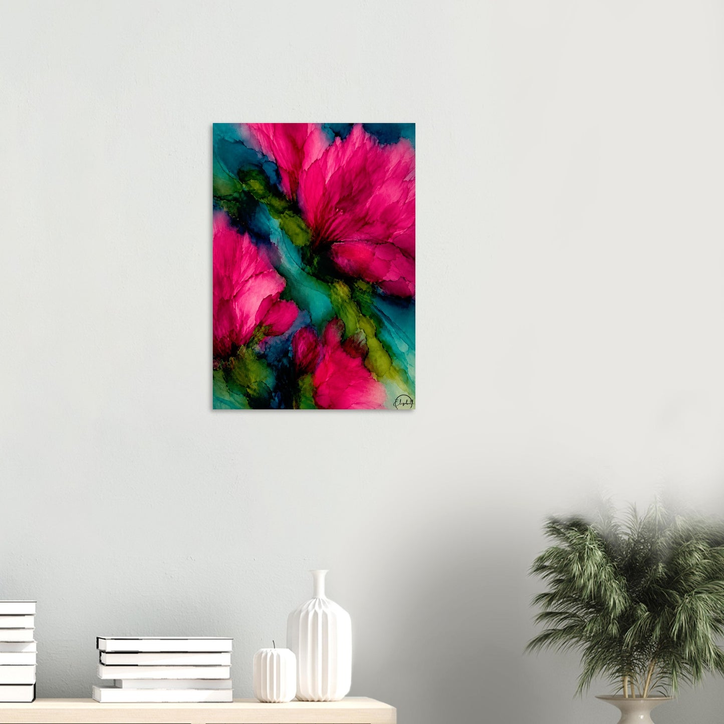 A vertical canvas wall art print featuring vibrant abstract hot pink flowers with teal and green watercolor backgrounds, displayed on a light gray wall above a styled shelf with books, white vases, and a potted plant.