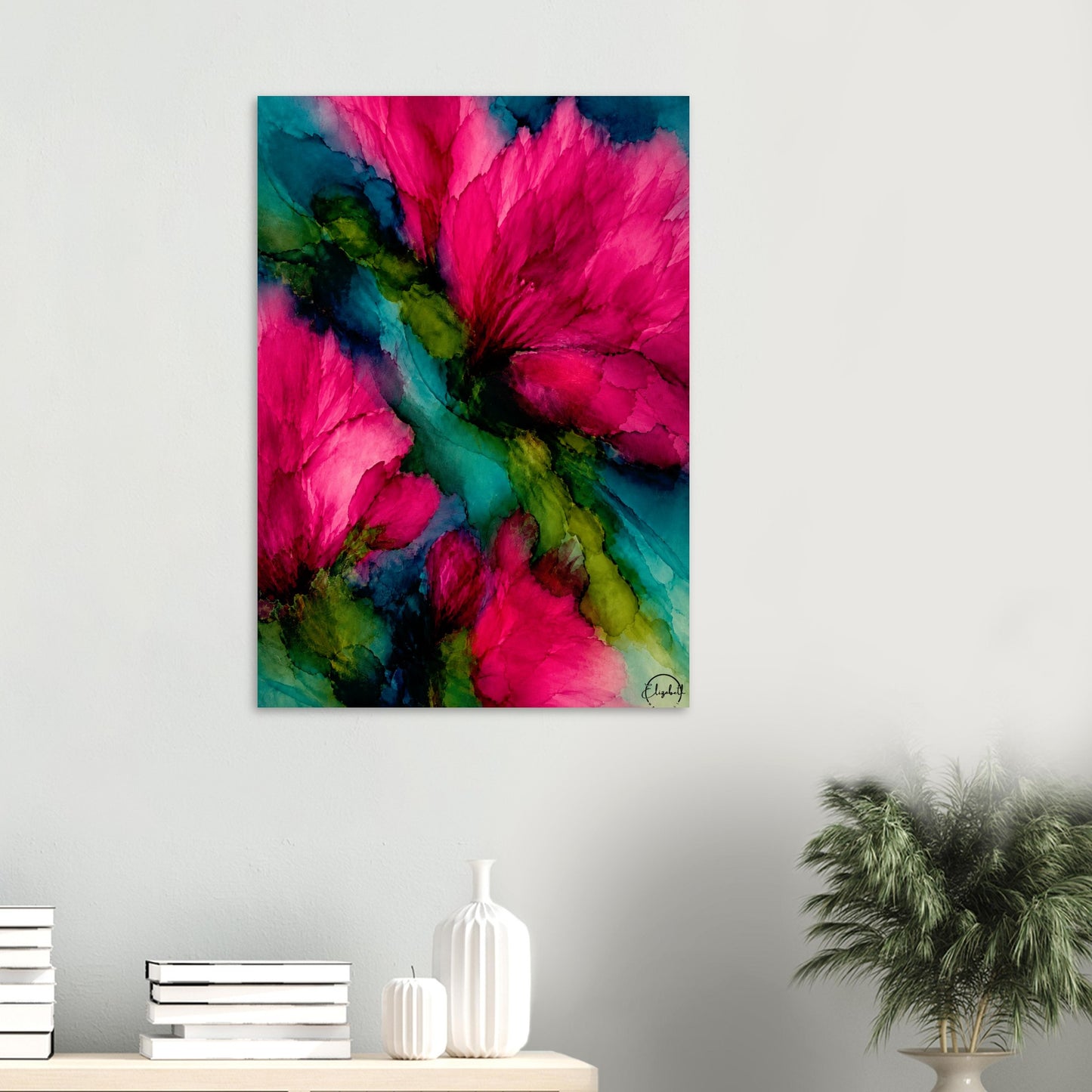 A vertical canvas wall art print featuring a vibrant abstract floral design with bright pink blossoms and teal/green watercolor washes, displayed on a light gray wall above a console table with books and a plant.