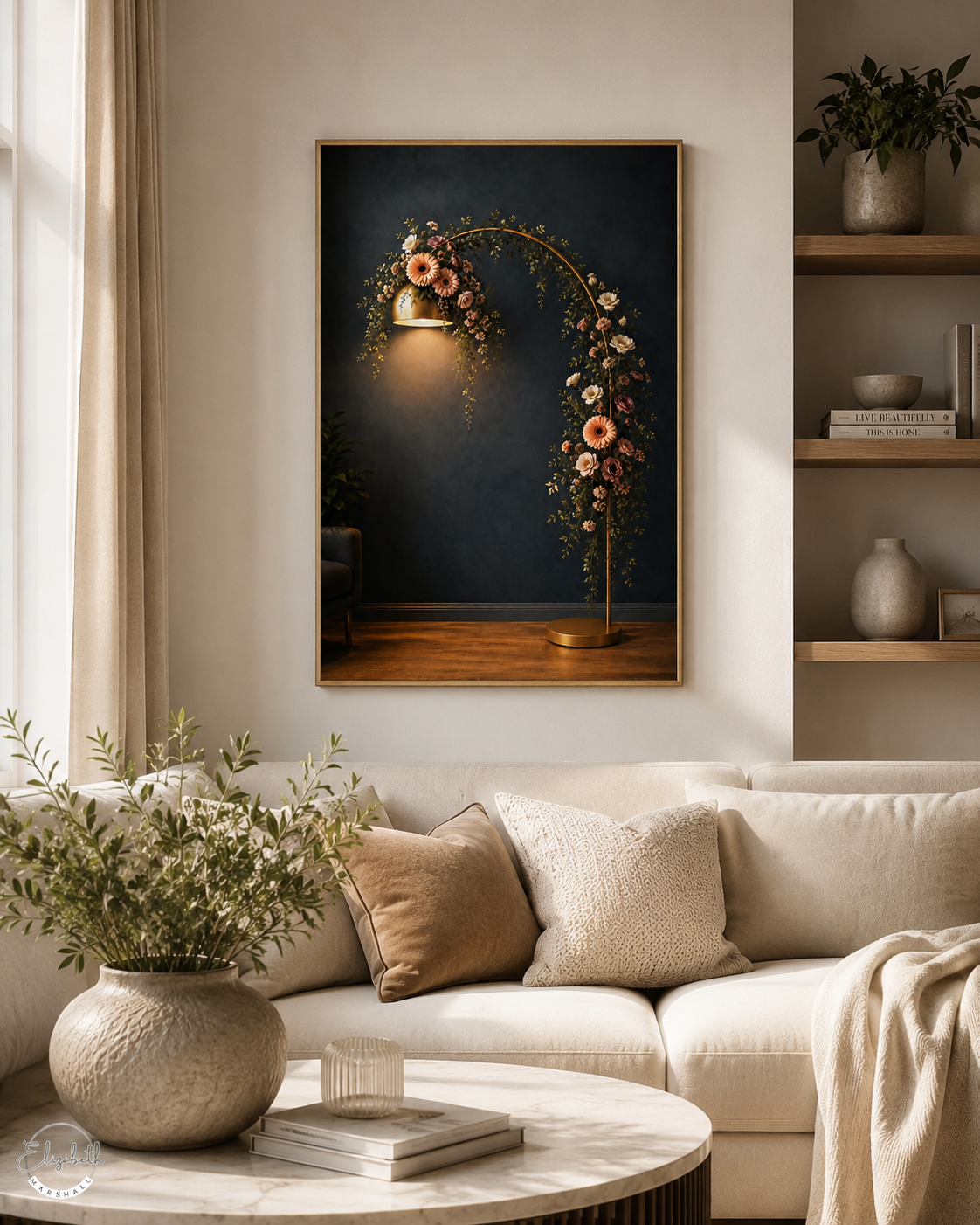 A framed wall art print depicting a golden floral arch with a glowing lantern against a dark navy background, displayed in a styled living room above a cream sofa with neutral-toned pillows and a marble coffee table.