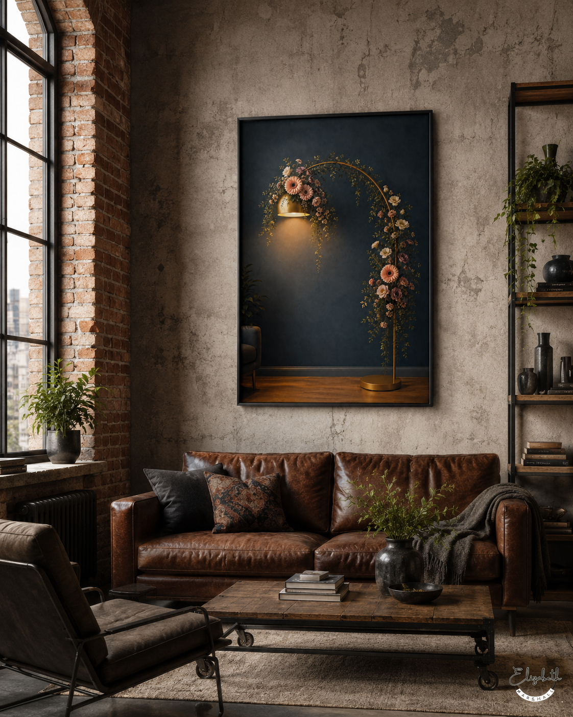 A framed wall art print depicting a glowing golden arch with pink and white flowers against a dark navy background, displayed in a rustic industrial living room above a brown leather sofa.