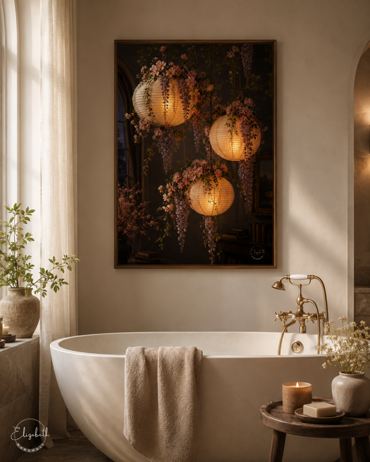 A framed wall art print depicting three glowing paper lanterns and wisteria flowers, hung above a white freestanding bathtub in a softly lit bathroom setting.