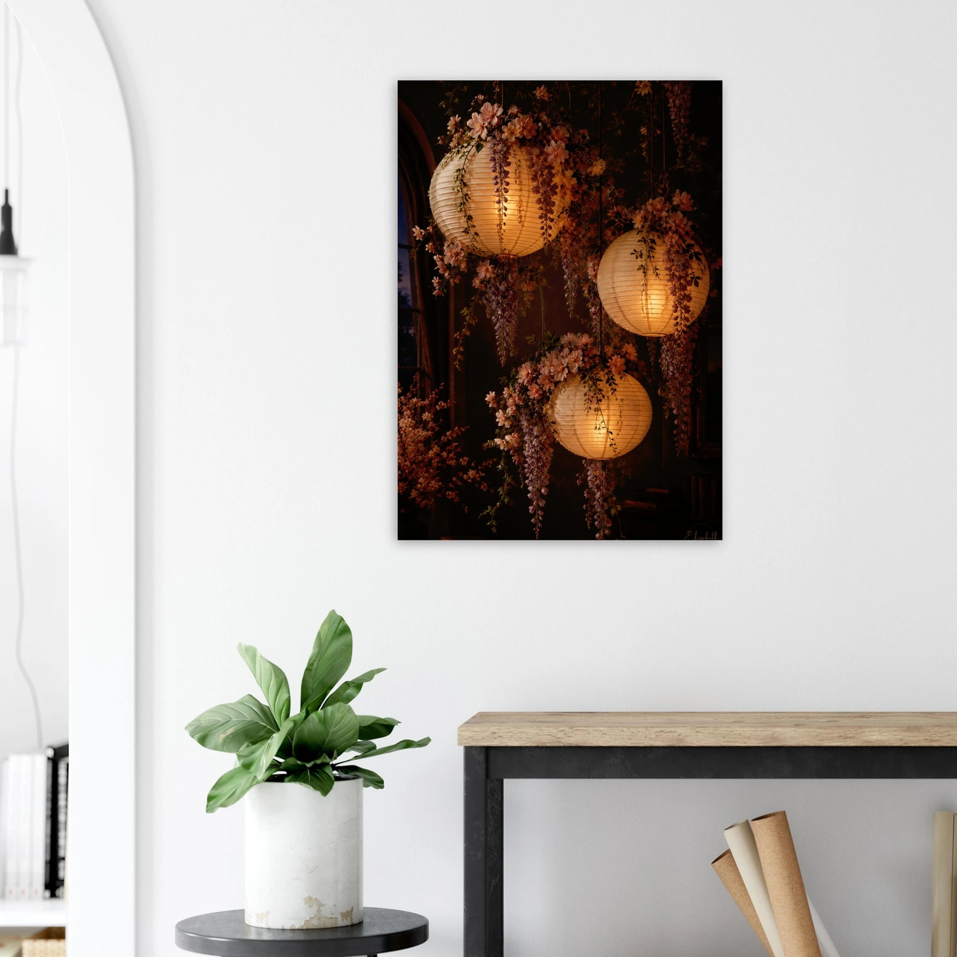 Three glowing paper lanterns hanging in a dim interior, decorated with cascading pink wisteria flowers and green leaves.