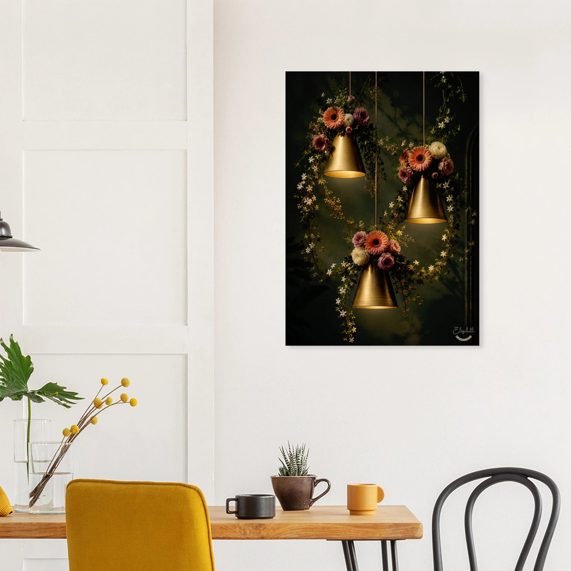 A vertical wall art print depicting three glowing gold pendant lights hanging among dark foliage and colorful flowers, displayed on a white wall above a dining table with chairs and mugs.