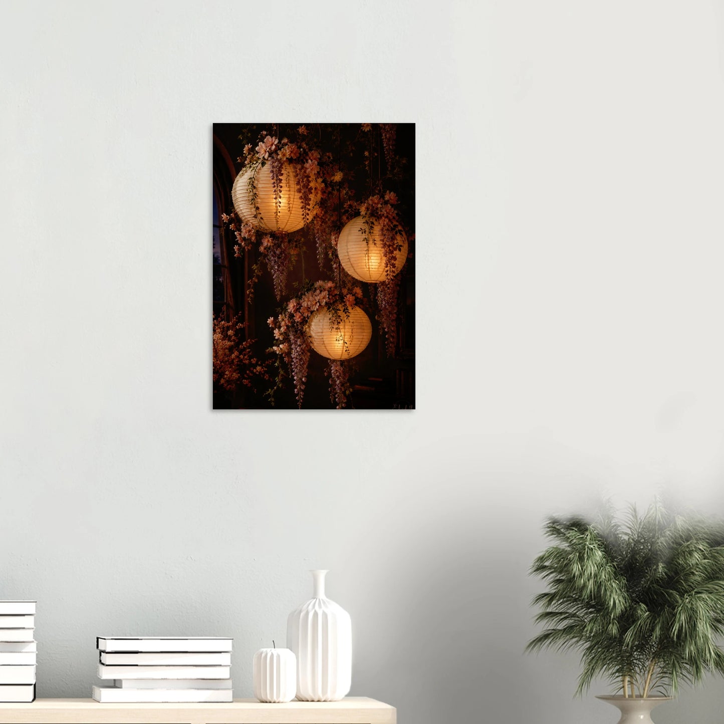 Three glowing paper lanterns hanging in a dim interior, decorated with cascading pink wisteria flowers and green leaves.