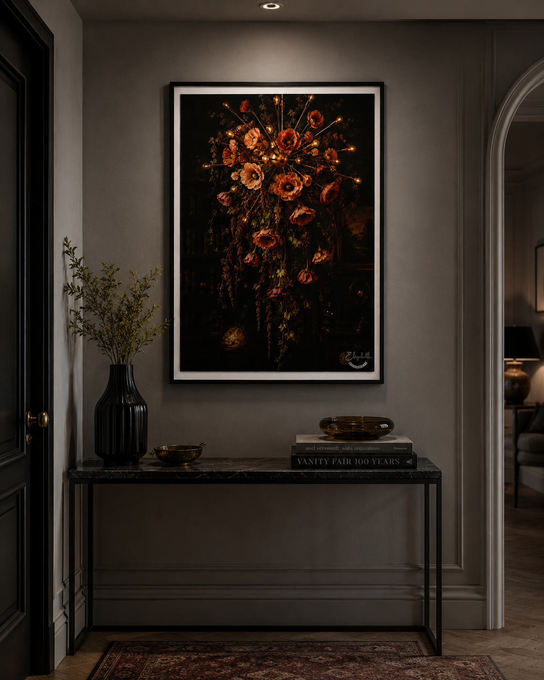 A framed dark floral art print hangs on a gray wall above a console table in a styled interior hallway. The artwork features a cluster of red, orange, and gold flowers on a black background, with a white frame border.