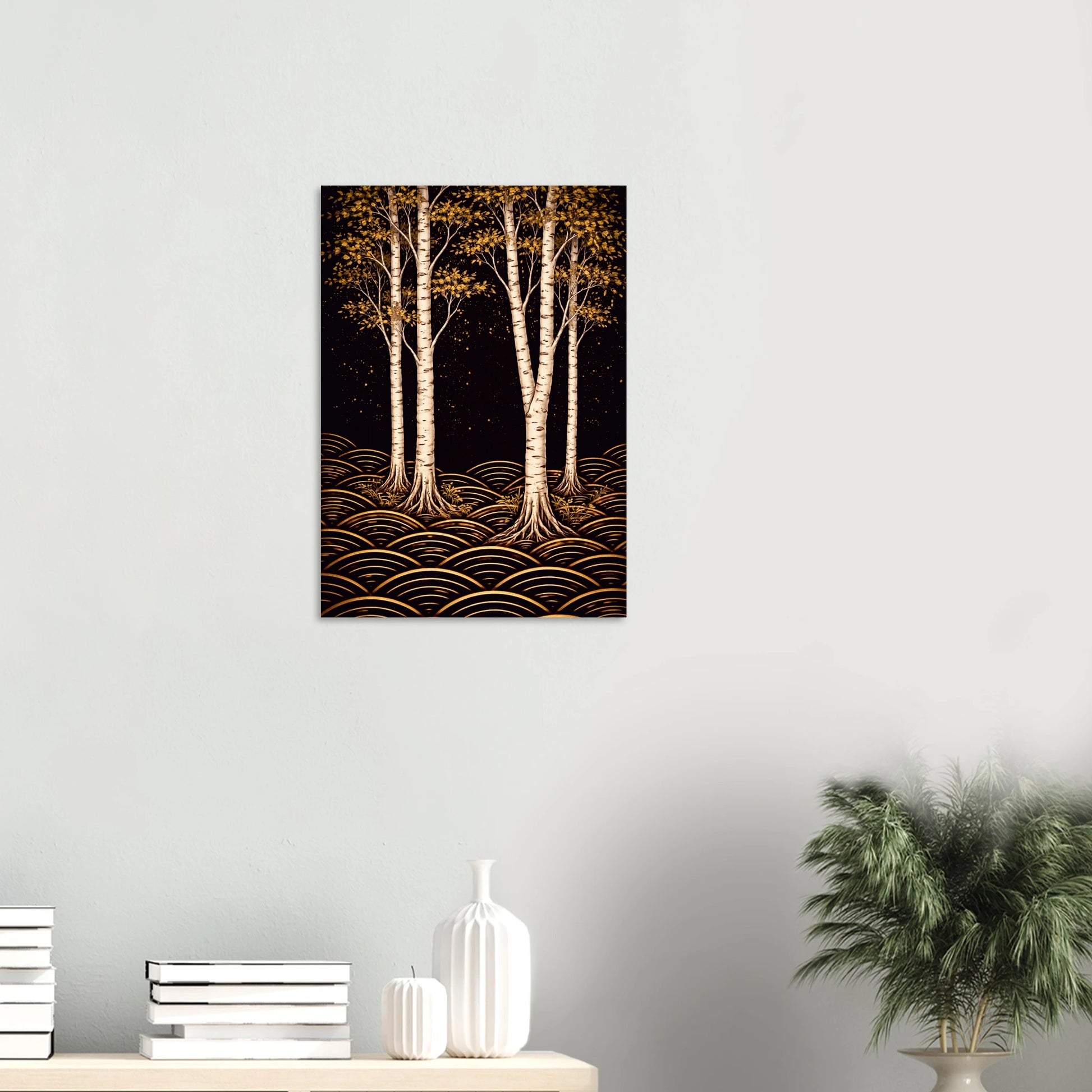 A vertical canvas art print depicting three white birch trees with golden-brown foliage and wave-like gold patterns on a black background, displayed on a light gray wall above a console table with books and a plant.