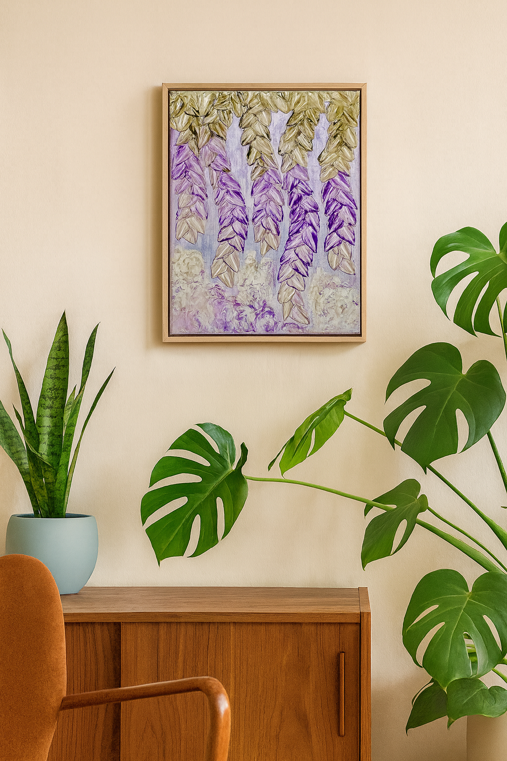A framed botanical art print featuring purple wisteria flowers and green leaves, hanging on a beige wall above a wooden cabinet with potted plants in a styled room.