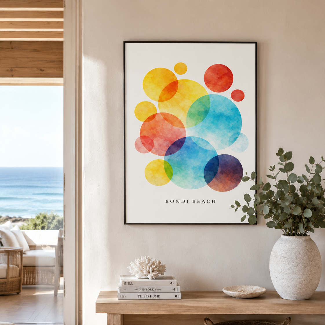 A framed art print featuring colorful overlapping watercolor circles with the text 'BONDI BEACH' at the bottom, displayed on a beige wall in a modern living room setting.