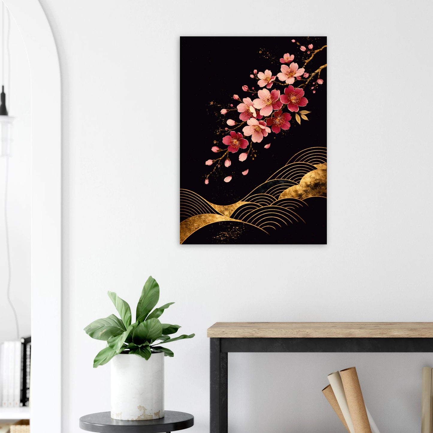 A vertical wall art print featuring pink cherry blossoms and gold wave-like patterns on a black background, displayed in a styled interior setting above a console table with a potted plant.