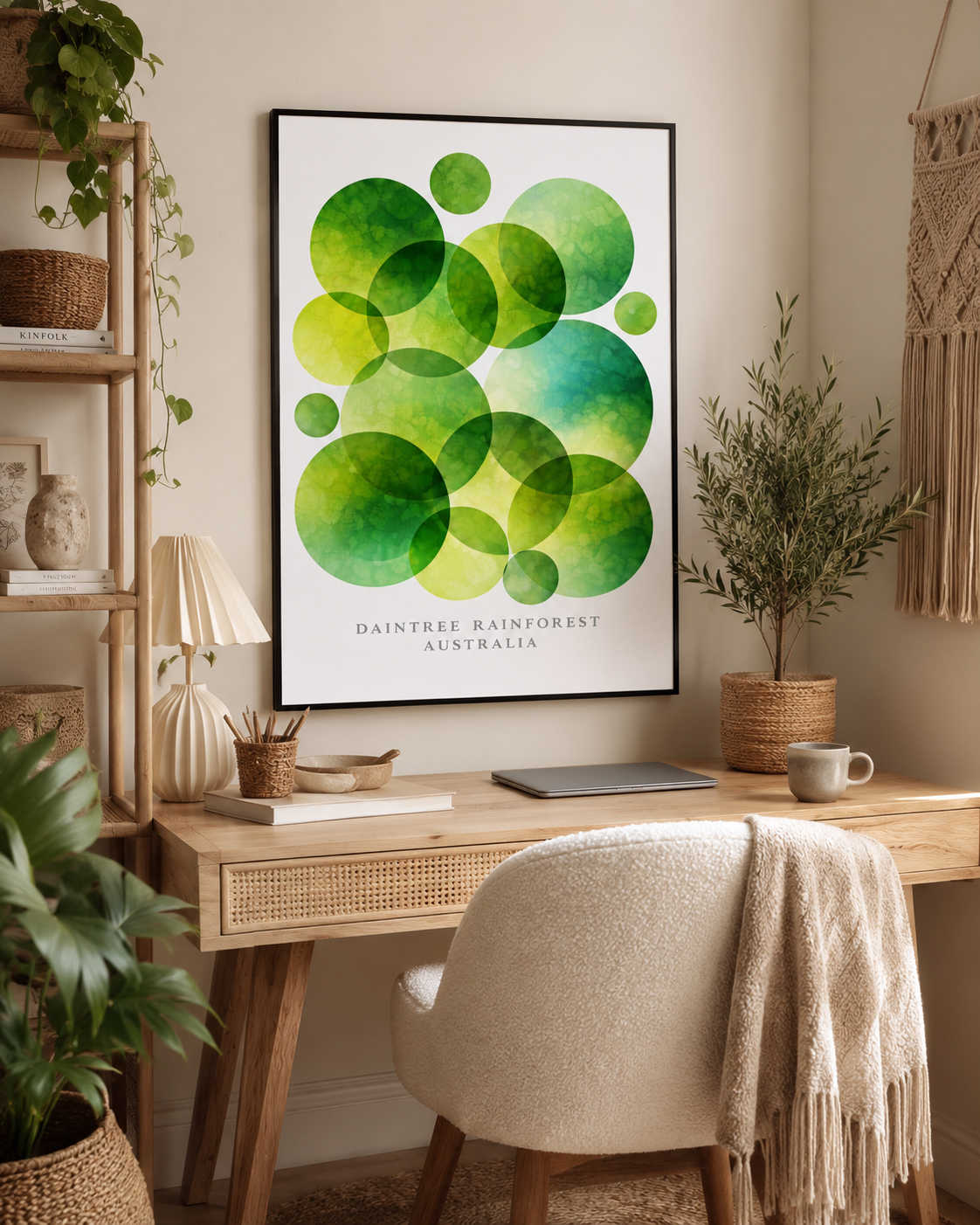 A framed art print featuring green watercolor rainforest circles on a white background, hanging on a beige wall above a wooden desk in a styled home office setting.