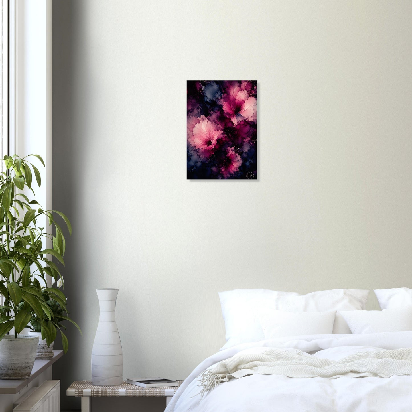 A small vertical wall art print with an abstract floral design in pink, magenta, and dark purple tones, displayed on a light beige bedroom wall above a bed with white bedding, next to a potted plant and a white vase.