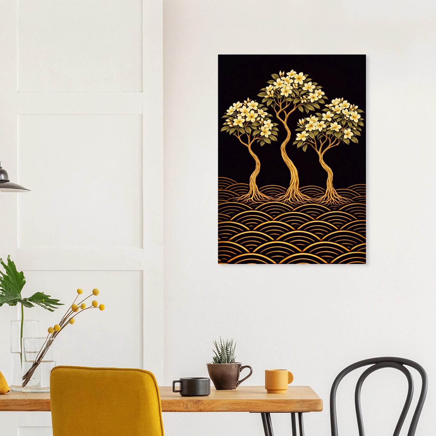 A vertical wall art print featuring three stylized golden trees with white blossoms above a black background and gold wave pattern, displayed on a white wall above a dining table with chairs and mugs.