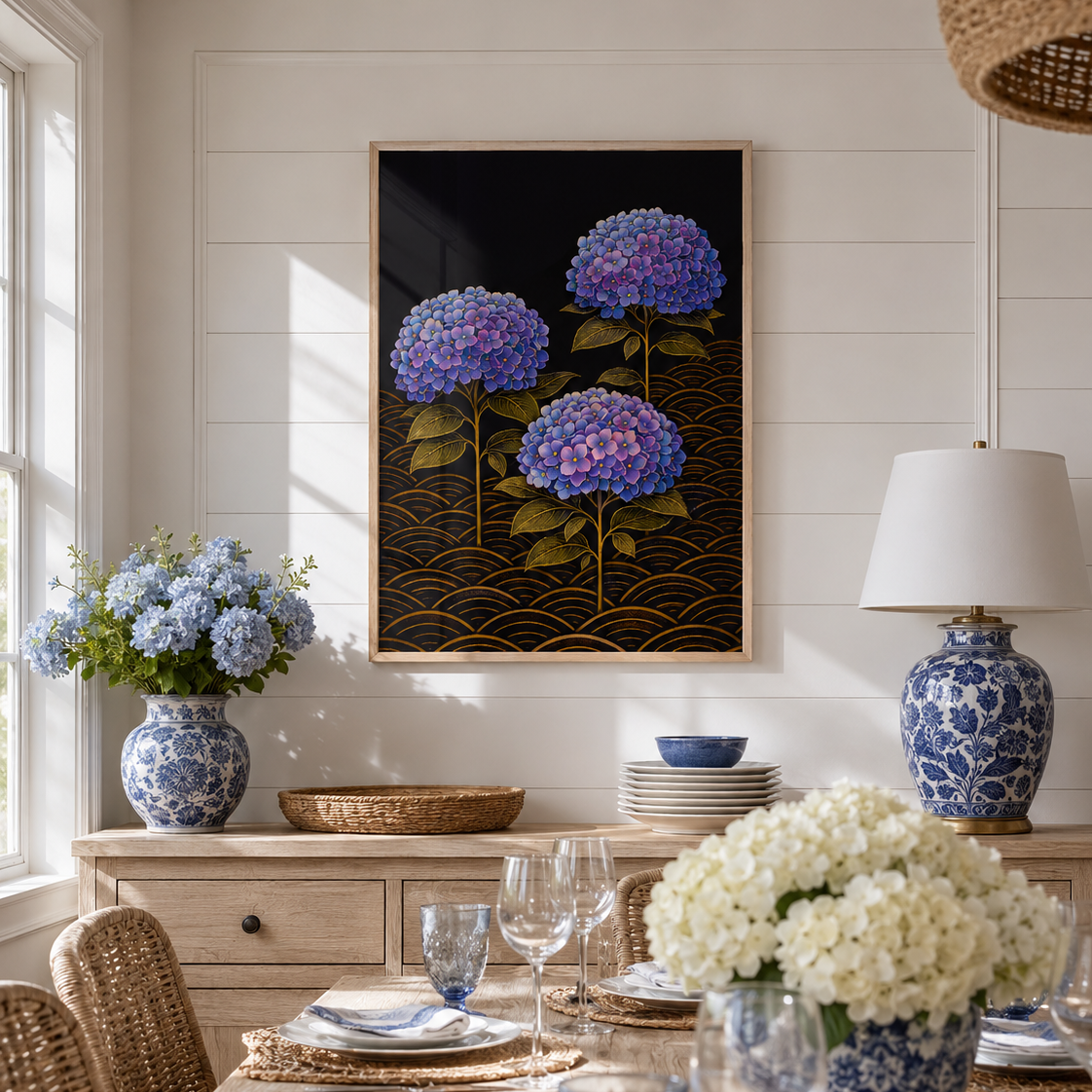 A framed wall art print featuring purple and blue hydrangeas on a black background with gold wave patterns, displayed in a bright dining room above a set dining table with blue and white floral arrangements.
