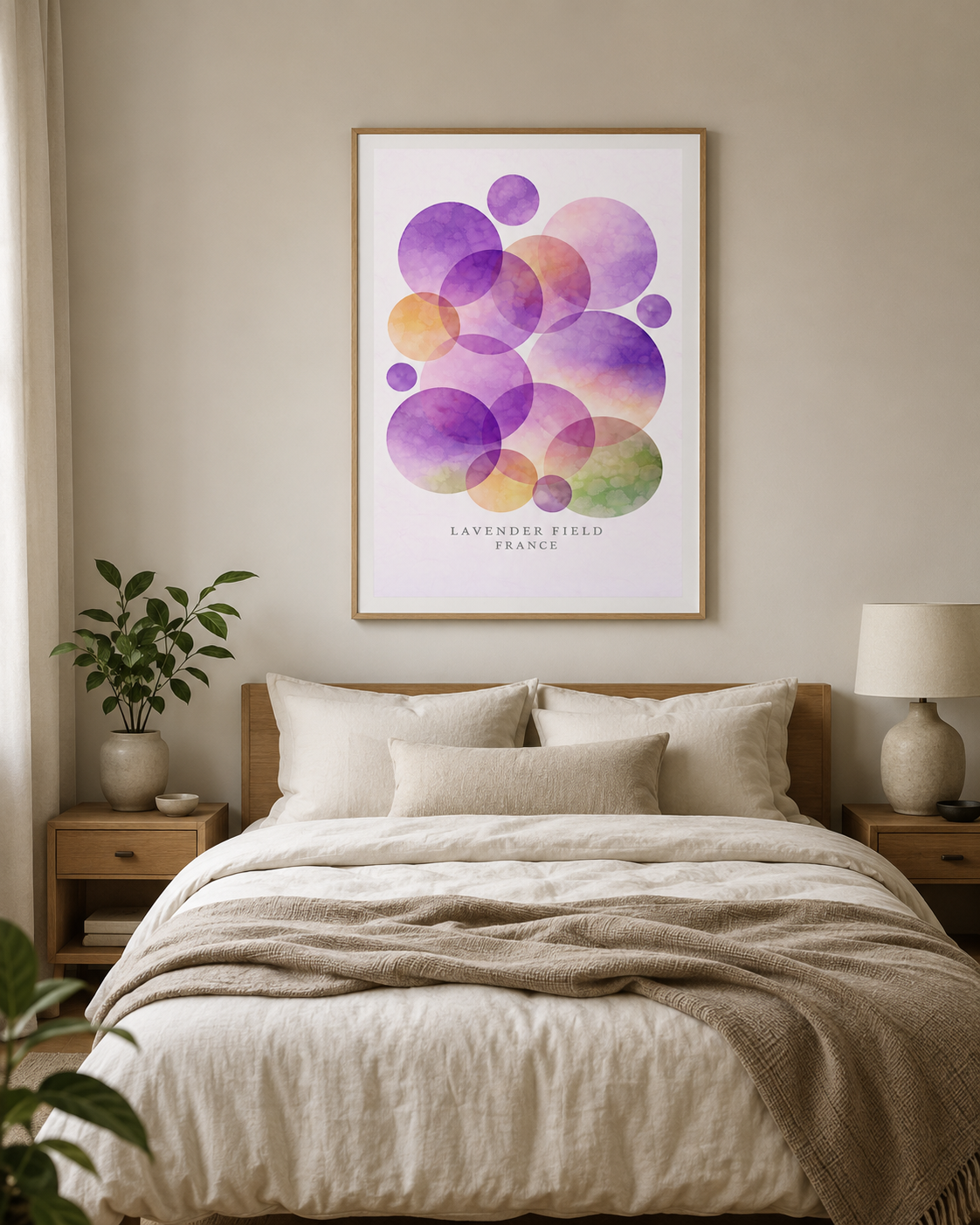 A framed abstract art print featuring overlapping watercolor circles in purple, pink, orange, and green on a white background, hanging on a beige wall above a neatly made bed with neutral linens and wooden bedside tables.
