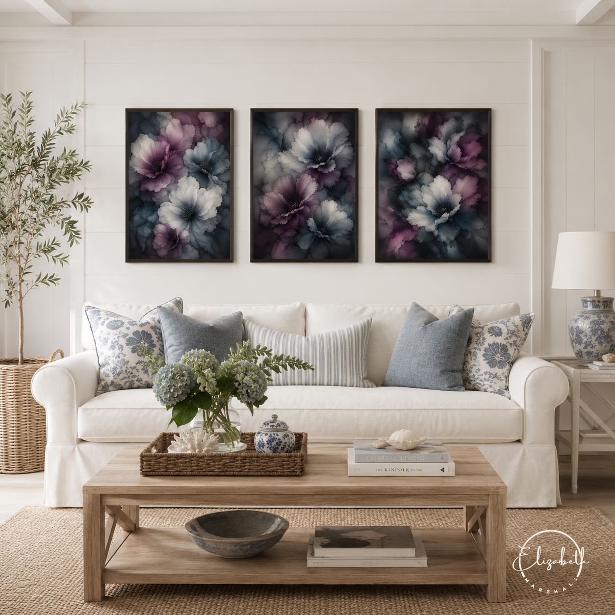 A styled living room scene featuring three framed vertical canvas prints with abstract floral artwork in purple, blue, and gray tones, hung above a white sofa with patterned pillows.