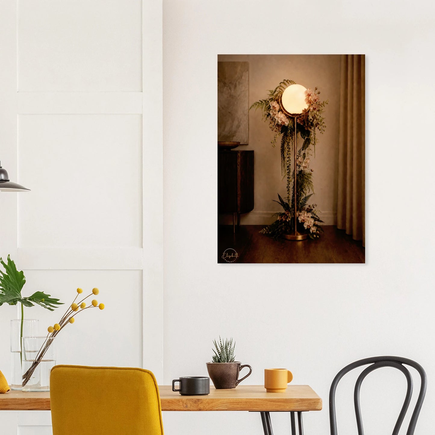 A vertical wall art print depicting a vintage-style floor lamp adorned with floral arrangements, displayed on a light gray wall above a console table with decorative vases and a potted plant.