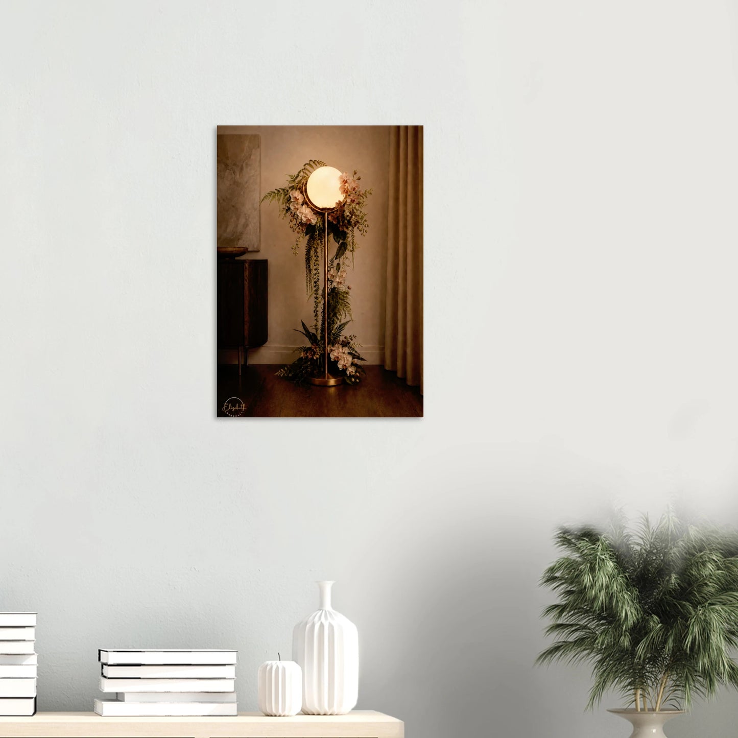 A vertical wall art print depicting a vintage-style floor lamp adorned with floral arrangements, displayed on a light gray wall above a console table with decorative vases and a potted plant.