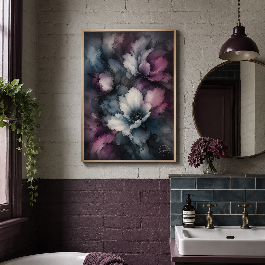 A framed abstract floral wall art print with swirling purple, blue, and white brushstrokes hangs on a bathroom wall above a white sink and dark wood vanity. The room has a two-tone brick wall, a round mirror, a hanging pendant light, and a bathtub with a draped towel.