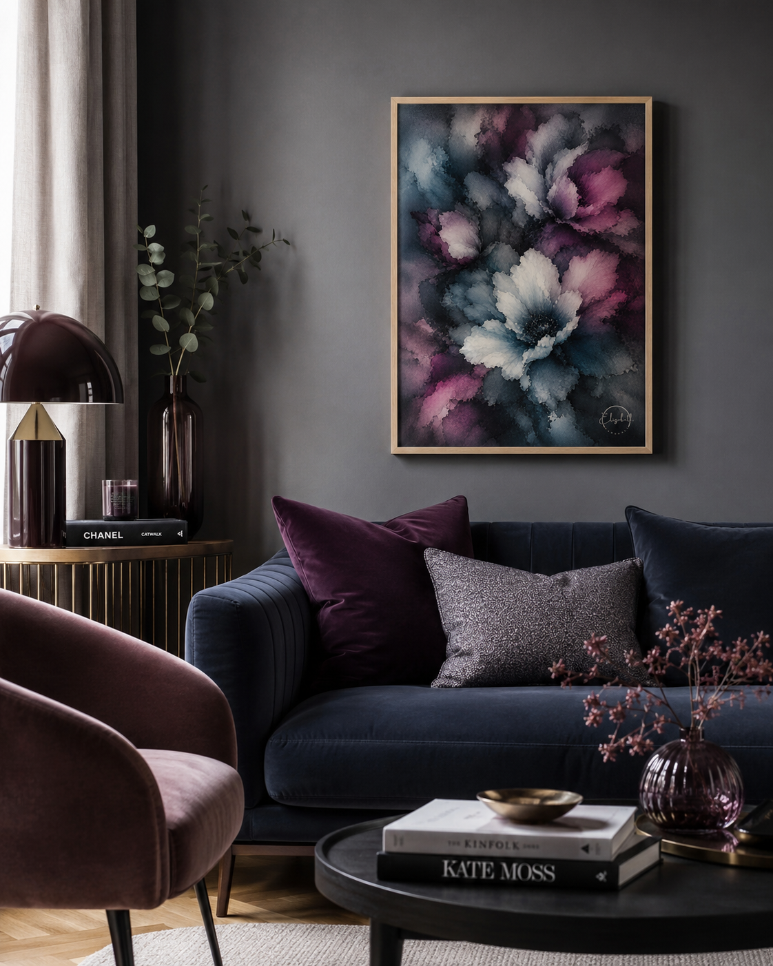 A framed abstract floral painting with shades of purple, blue, and white hangs on a dark gray wall above a navy blue sofa in a styled living room setting.