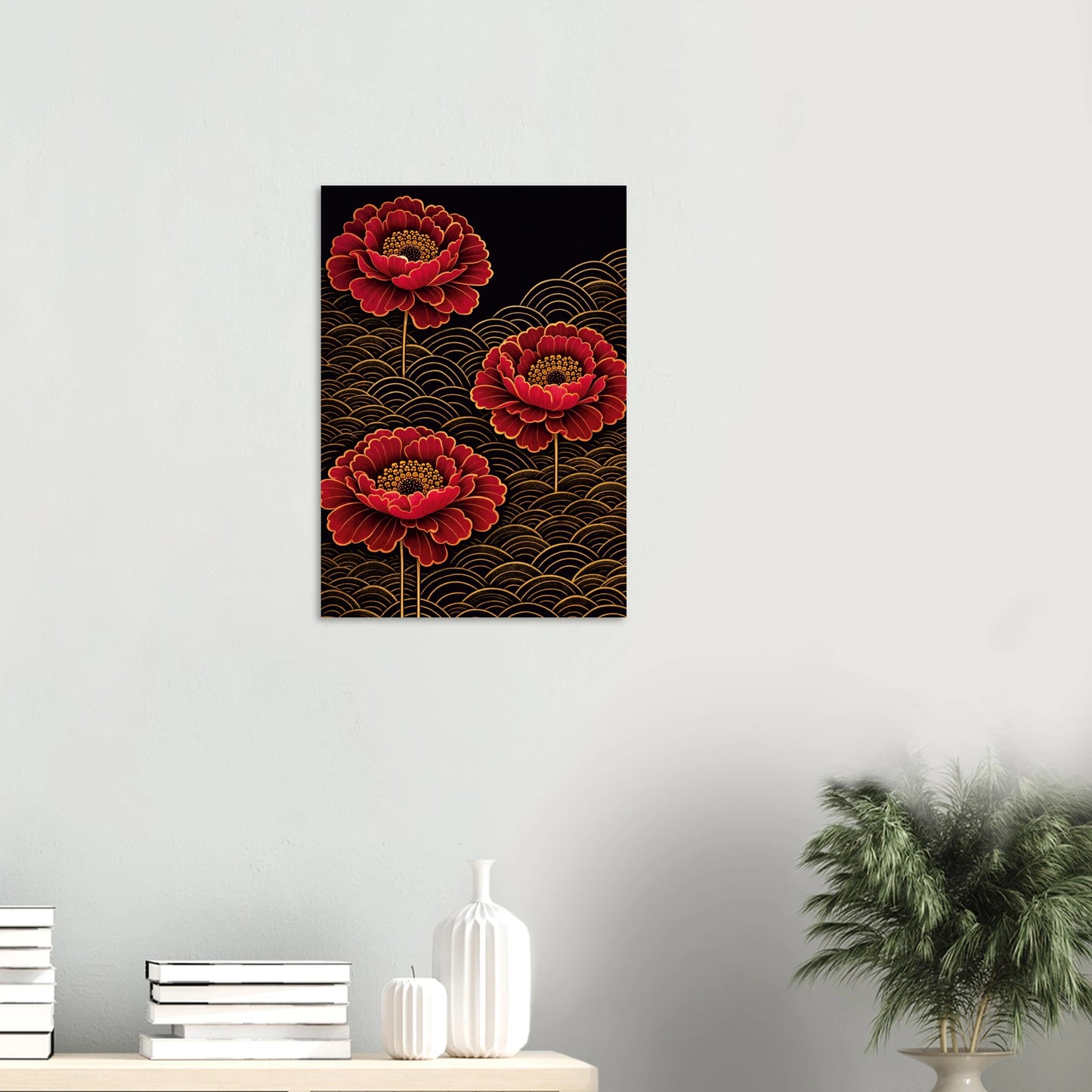 A vertical wall art print featuring three red peony-like flowers over a black background with gold wave patterns, displayed on a light gray wall above a console table with books, vases, and a potted plant.