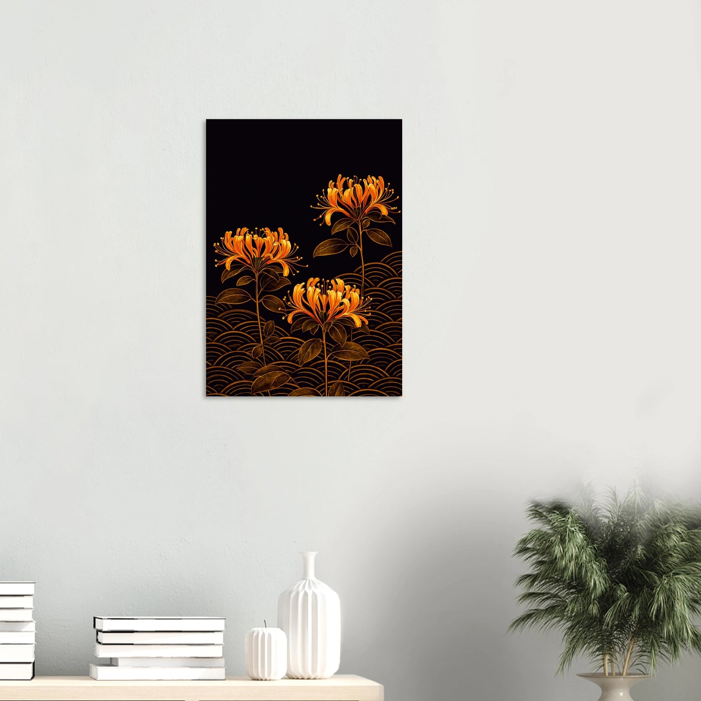 A vertical wall art print featuring three glowing orange flowers on a black background with gold wave patterns, displayed on a light gray wall above a console table with books, white vases, and a potted plant.