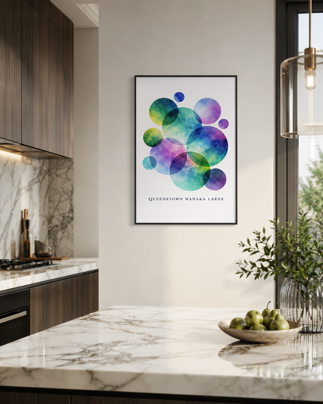 A framed art print featuring a colorful watercolor design of overlapping circles representing Queenstown Wanaka Lakes, displayed on a light gray wall in a modern kitchen setting.