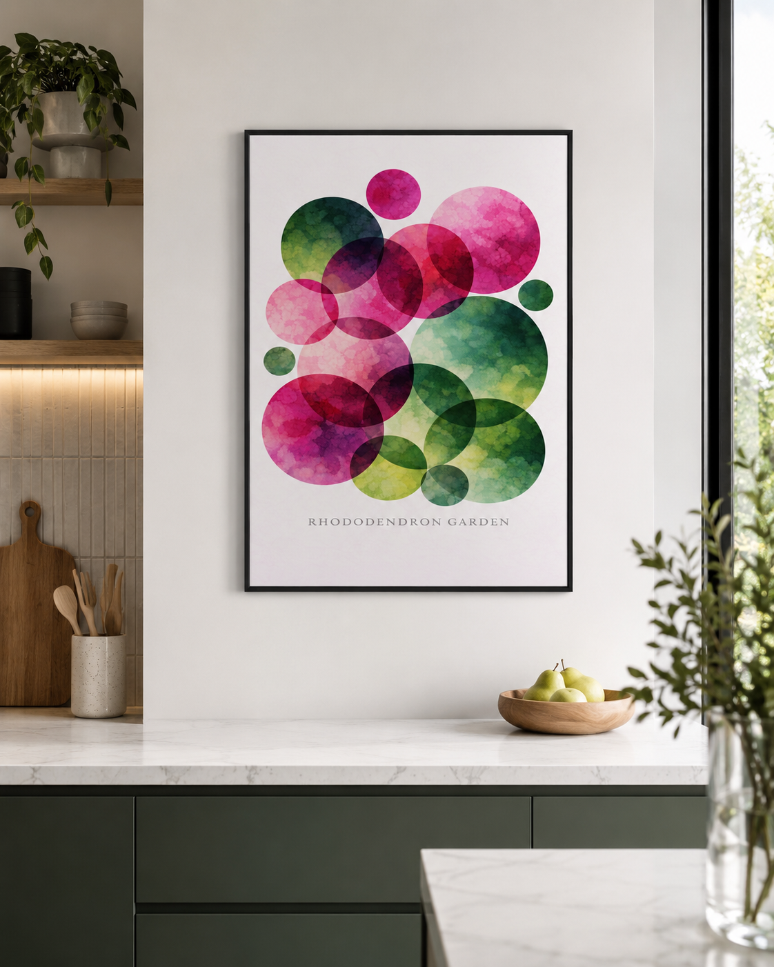 A framed abstract art print featuring overlapping watercolor circles in pink, green, and purple, hanging on a white kitchen wall above a marble countertop.