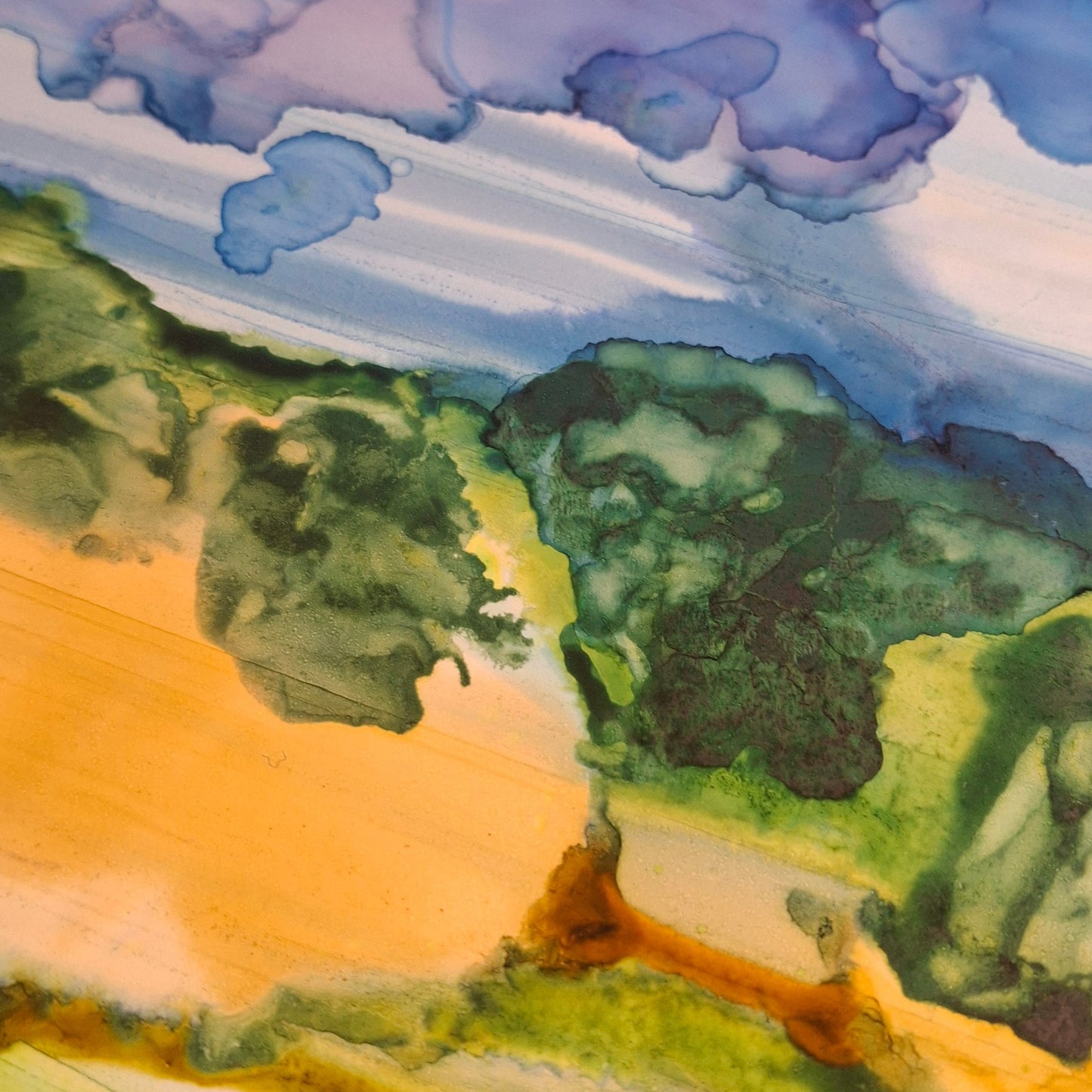 A close-up of a landscape painting showing green trees, yellow and orange fields, and blue-purple clouds, with a dark surface visible along the top edge.