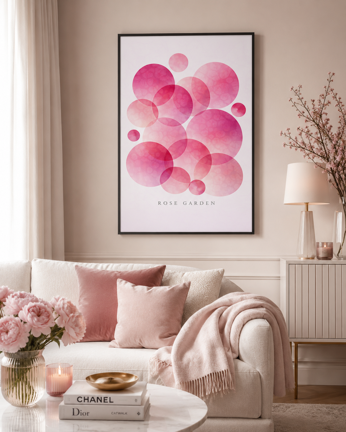 A framed art print featuring overlapping pink watercolor circles with the text 'ROSE GARDEN' at the bottom, displayed on a beige wall above a styled sofa in a living room setting.