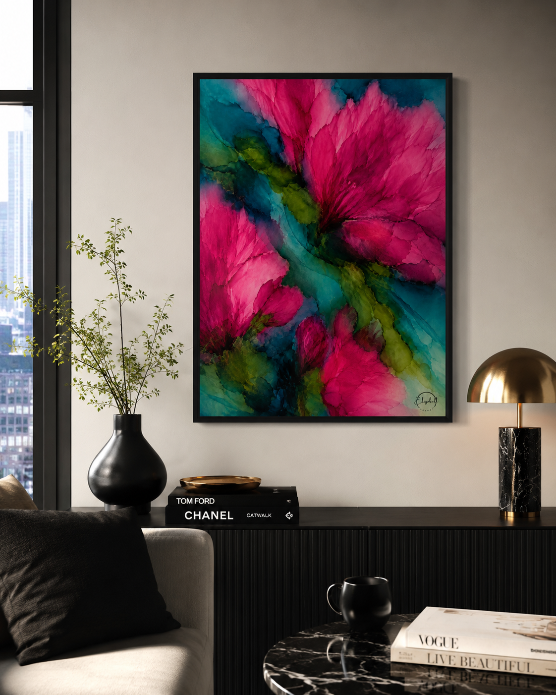 A framed abstract floral wall art print with vivid pink and teal watercolor-style petals hanging on a light gray wall above a dark console table in a modern living room setting.