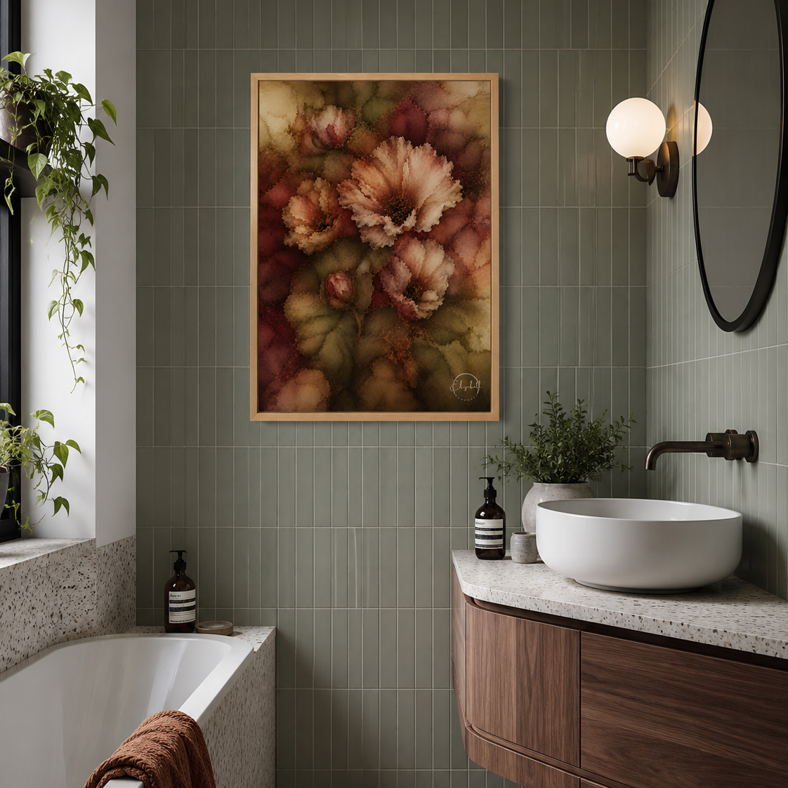 A framed floral wall art print hangs on a green tiled bathroom wall above a white vessel sink and wooden vanity. A bathtub, plants, wall sconces, and a round mirror are visible in the styled interior.