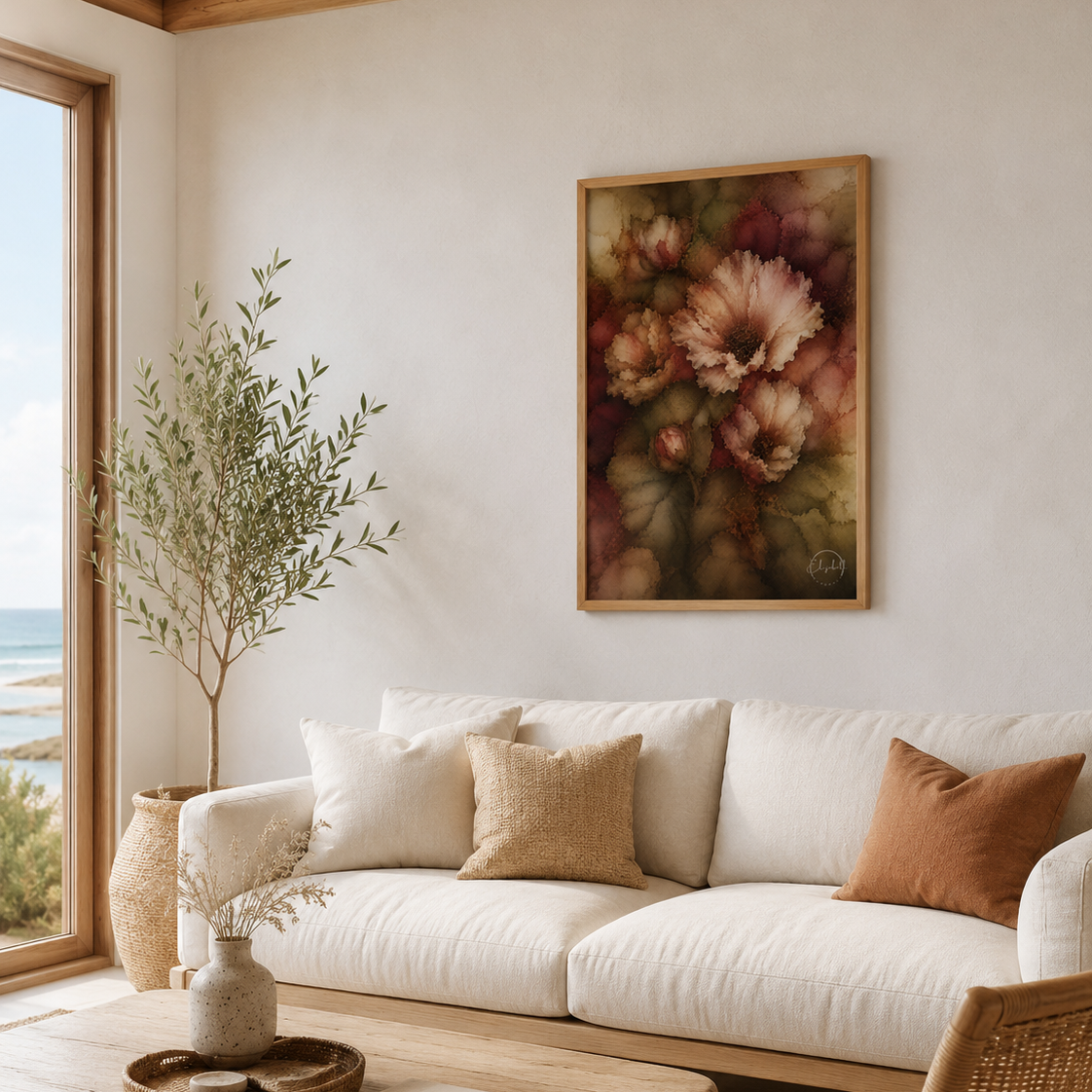 A framed floral art print hangs on a cream wall above a white sofa in a bright, modern boho living room with a wooden coffee table and rattan chair.